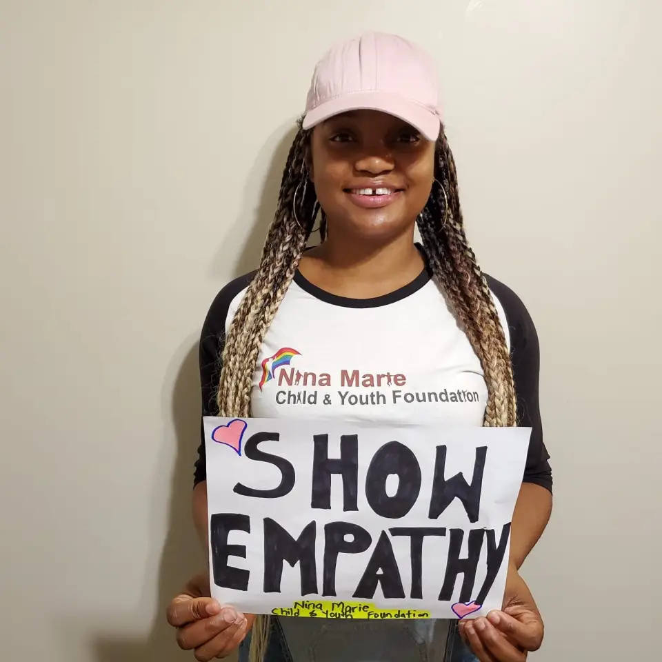 A young woman holding a handwritten sign that reads "Show empathy"