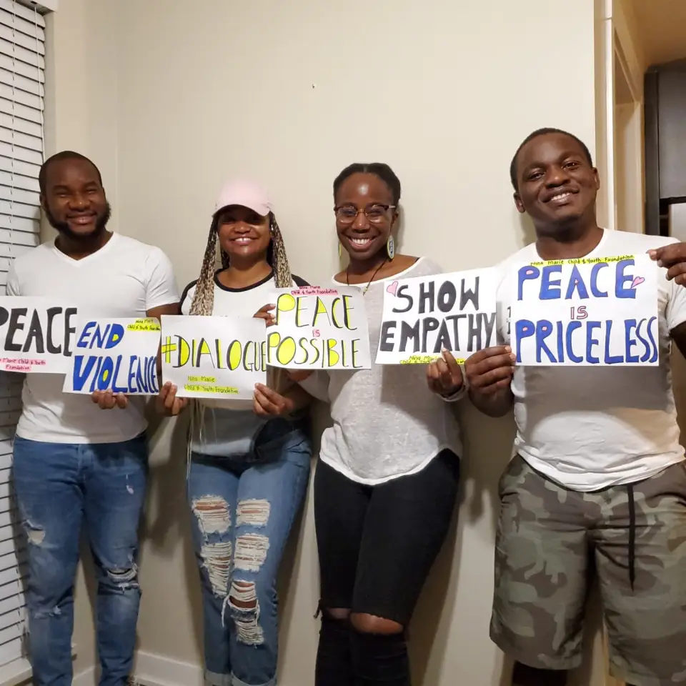 Four young people holding signs calling for peace and an end to violence