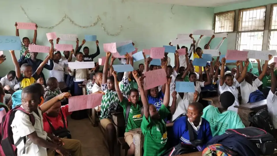 A packed classroom of children holding up coloured cards