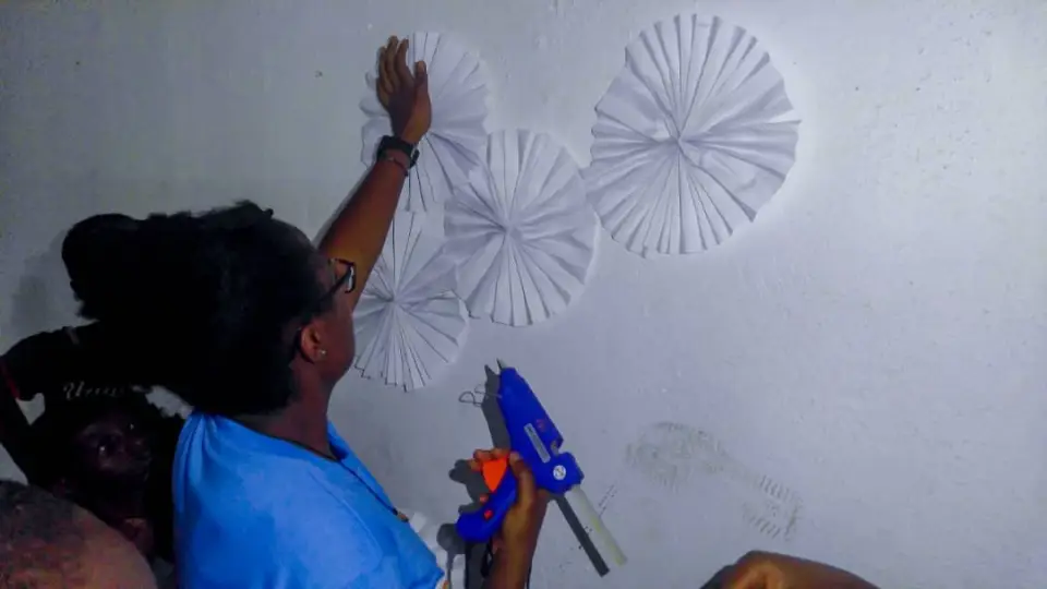 A volunteer fixing paper decorations to a wall