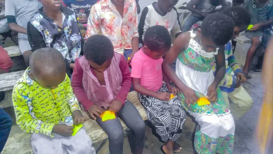 A row of young children seated together outdoors