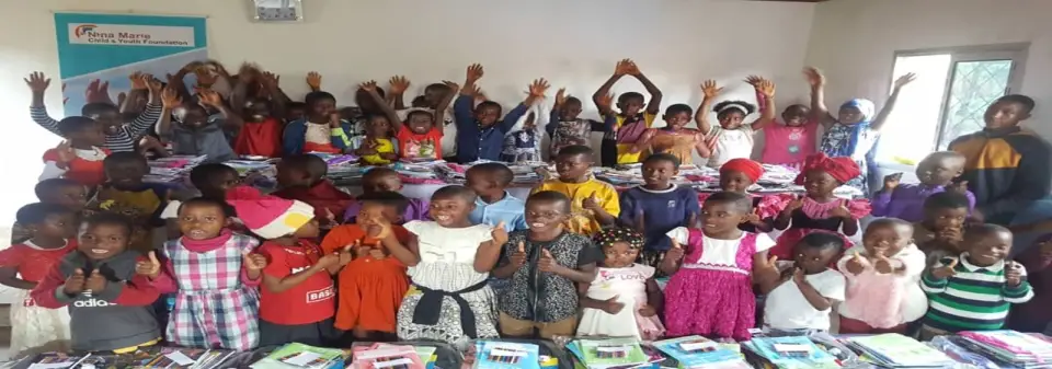 A large group of children with their new school bags and supplies, smiling at the camera