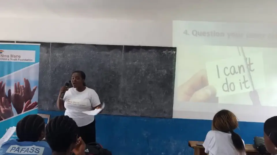 A facilitator speaking in a classroom beside a projector slide that reads "I can't do it"