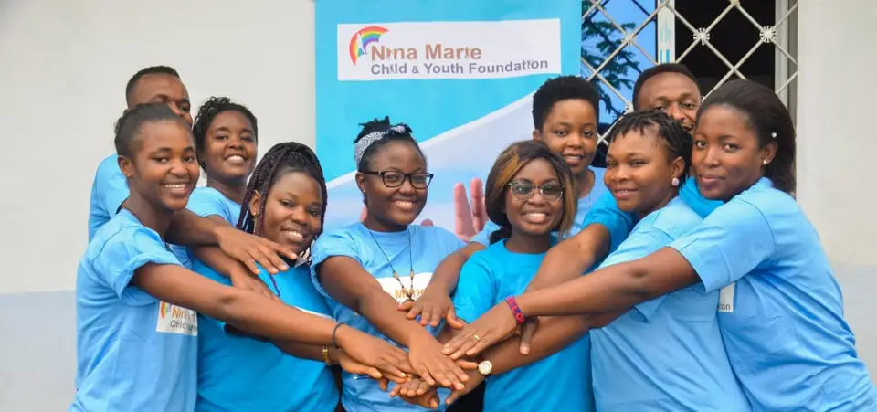 A team of volunteers in blue foundation t-shirts stacking their hands together